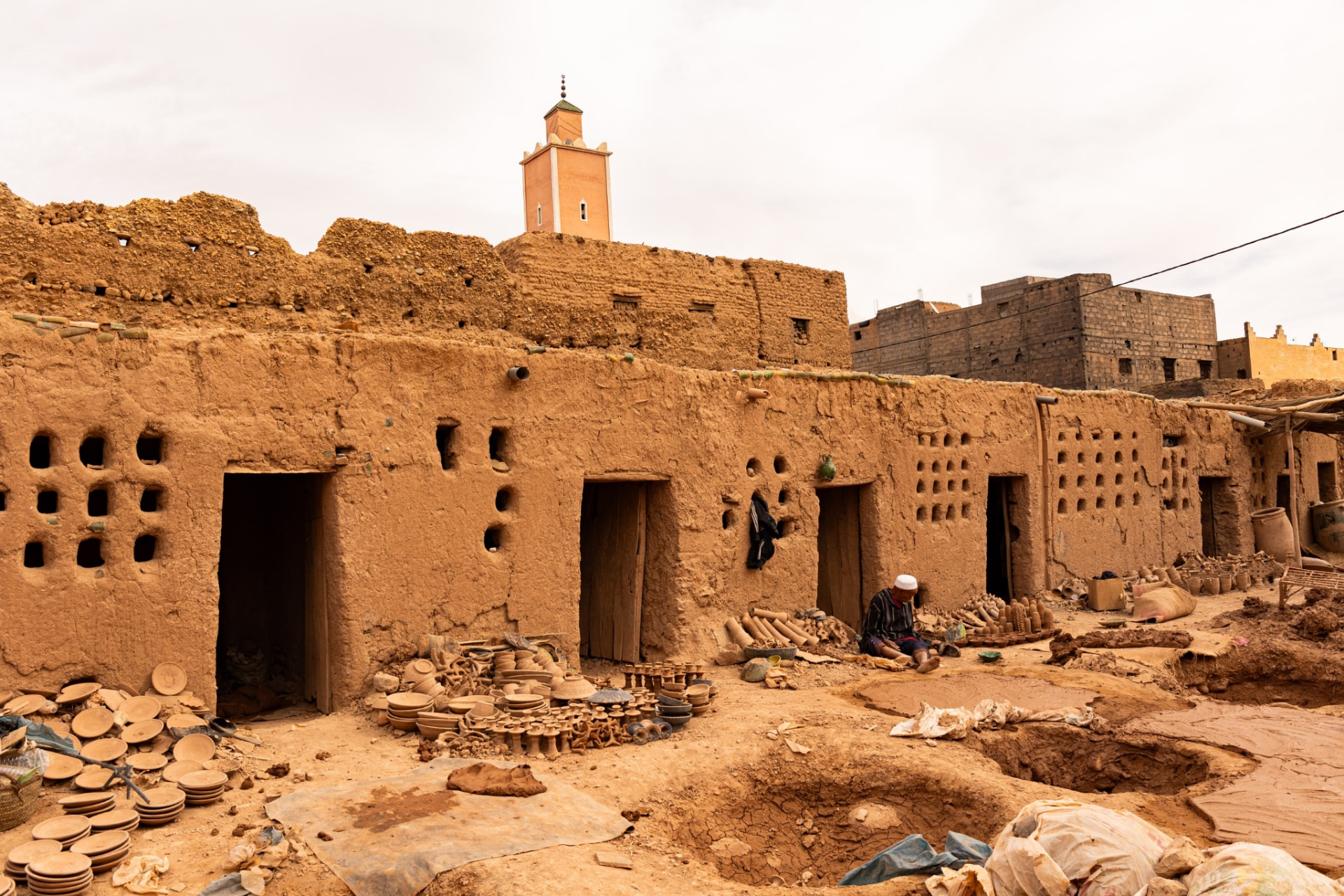 Clay pots drying in the sun before an earthen village and small minaret in the Draa Valley