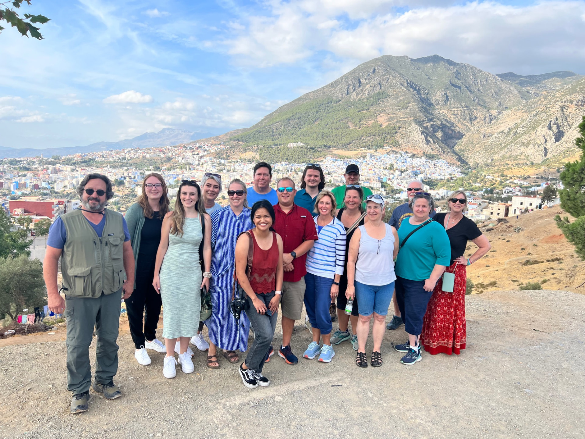 A group of Morocco Shiny Days guests at a hillside viewpoint above the blue town of Chefchaouen