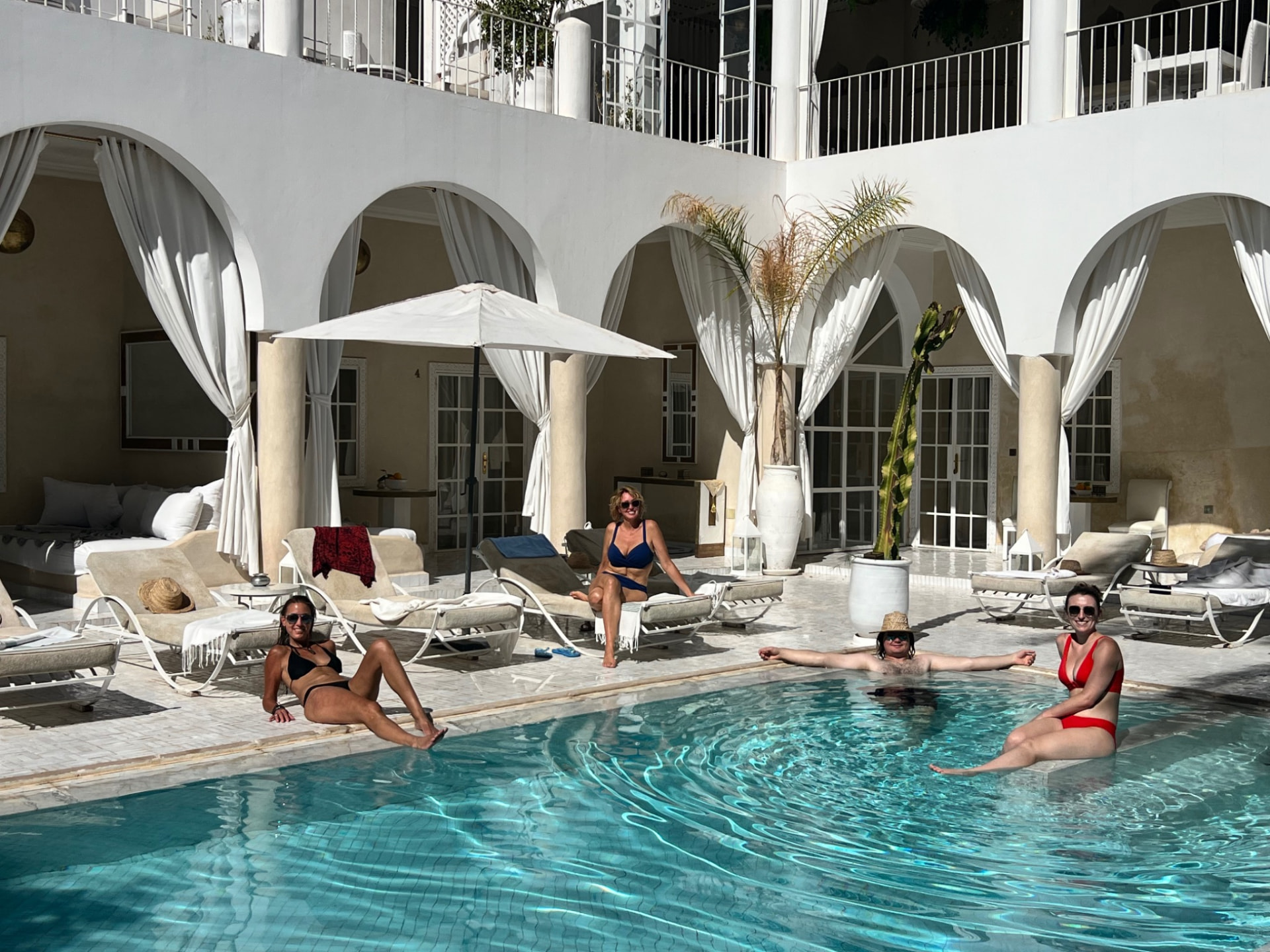 Guests relaxing beside the plunge pool in the white-walled courtyard of a Moroccan riad
