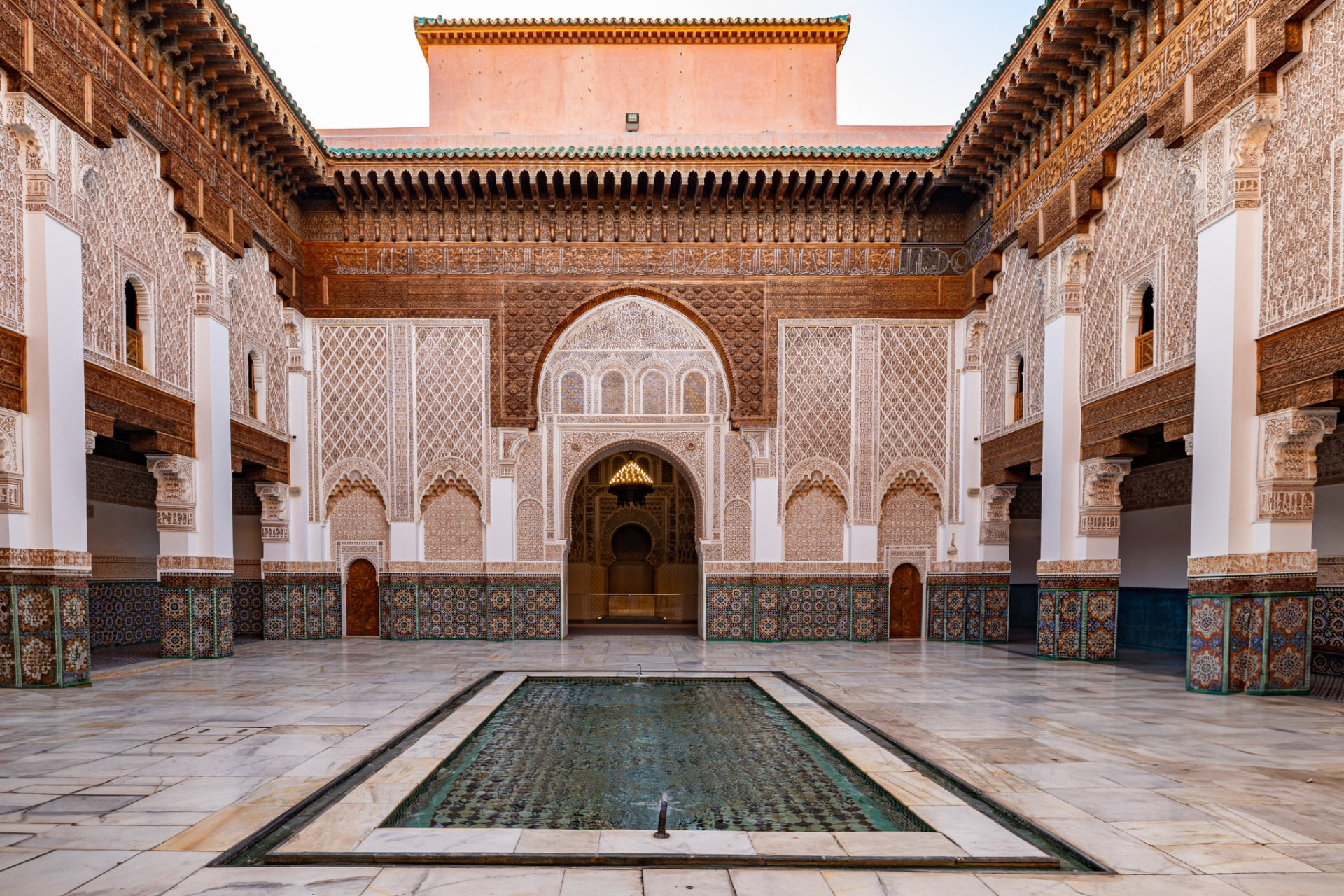 Carved plaster, zellige tilework and cedar detail in an ornate Moroccan palace courtyard