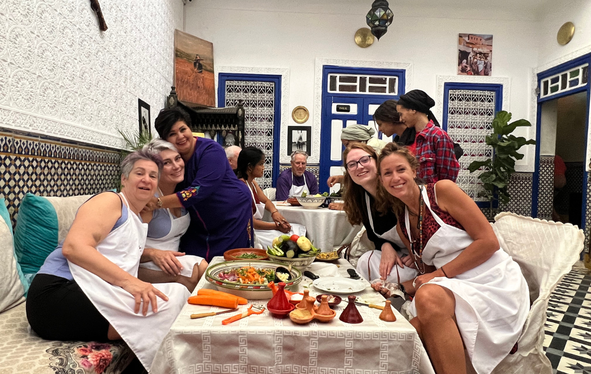Guests in white aprons seated around a table during a private cooking class in a Moroccan riad