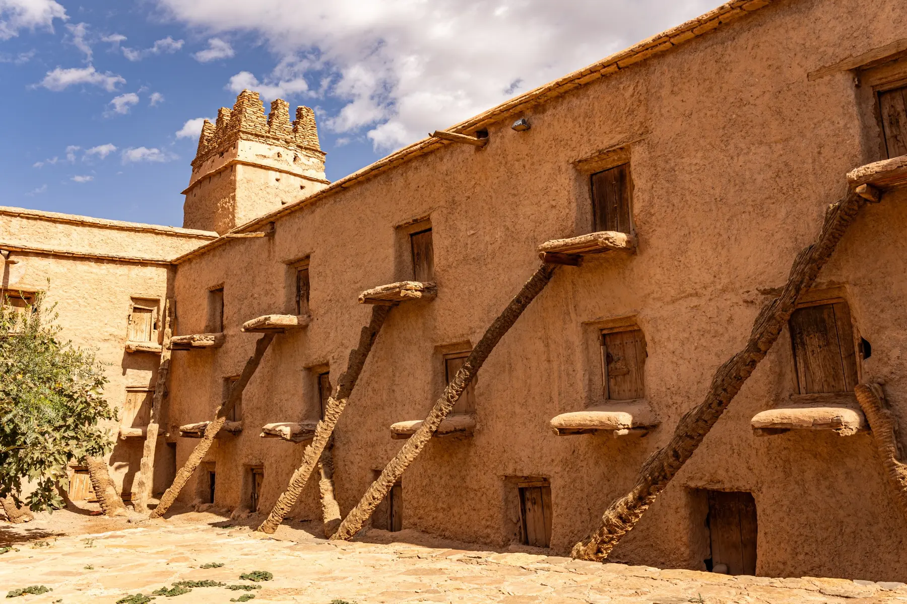 Rows of earthen storage chambers and wooden access steps inside Aït Kine Granary